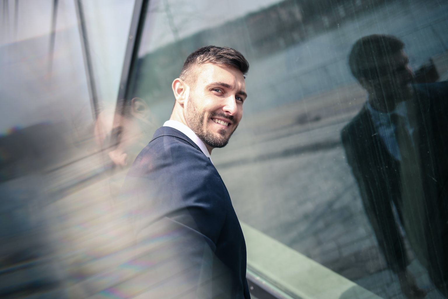 Cheerful businessman in formal wear standing in front of glass wall